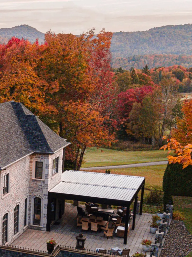 Pergola à lames motorisée Terra Summer sur une résidence en pierre à l'automne